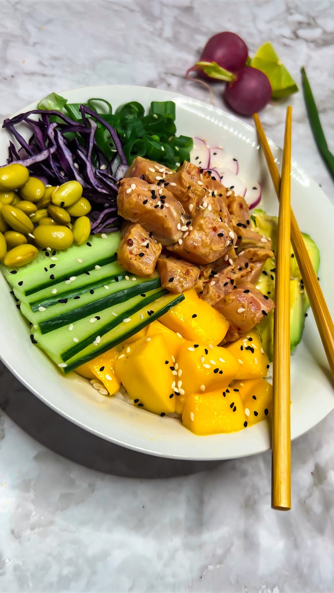 Farbenfrohe Poké Bowl mit Sushi-Reis, mariniertem Lachs, Avocado, Mango, Radieschen und Edamame-Bohnen, serviert mit frischen Frühlingszwiebeln und Limetten.