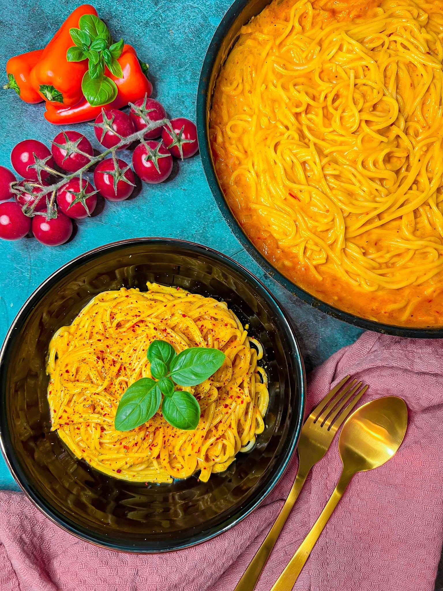 Cremige Spaghetti mit gerösteter Paprika-Tomatensoße, verfeinert mit Sahne und Knoblauch, serviert in einer Pfanne als italienisches Abendessen.