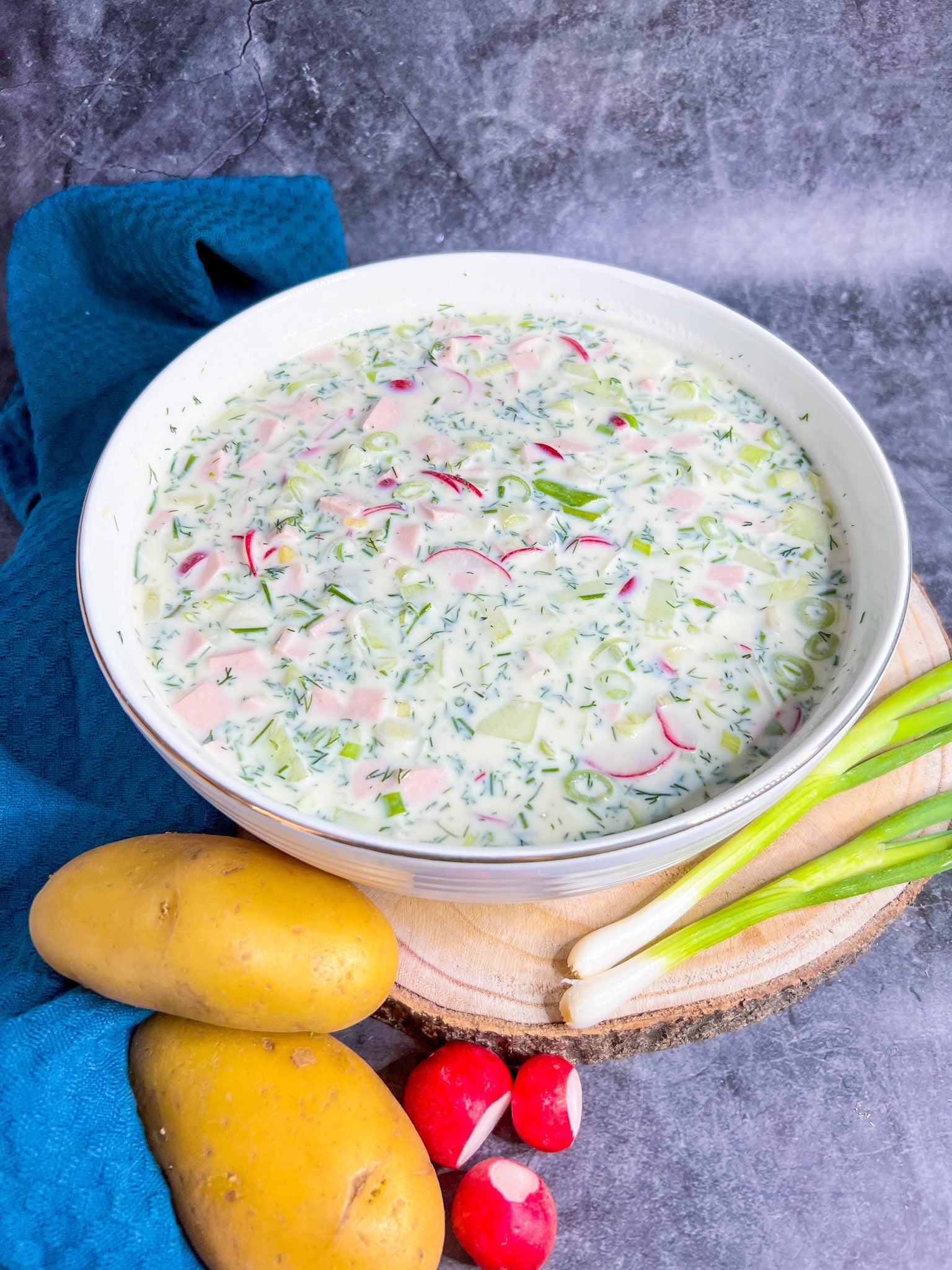 Okroschka – eine russische kalte Sommersuppe mit Buttermilch, Kartoffeln, Gurke, Radieschen und Dill, serviert in einer Schüssel.