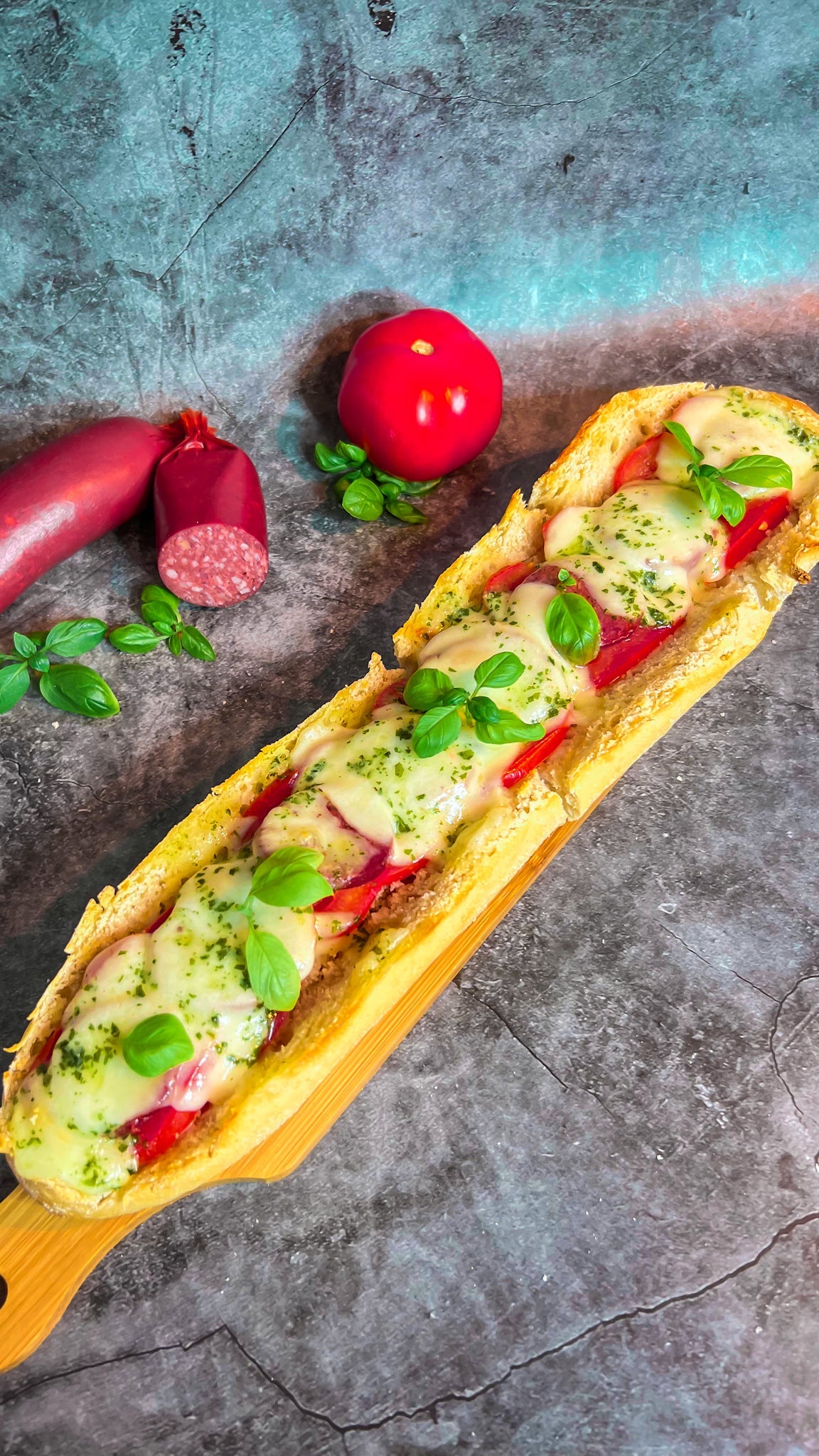 Ein frisch gebackenes Baguette mit Sucuk, Tomaten und Mozzarella, verfeinert mit Kräuterbutter.