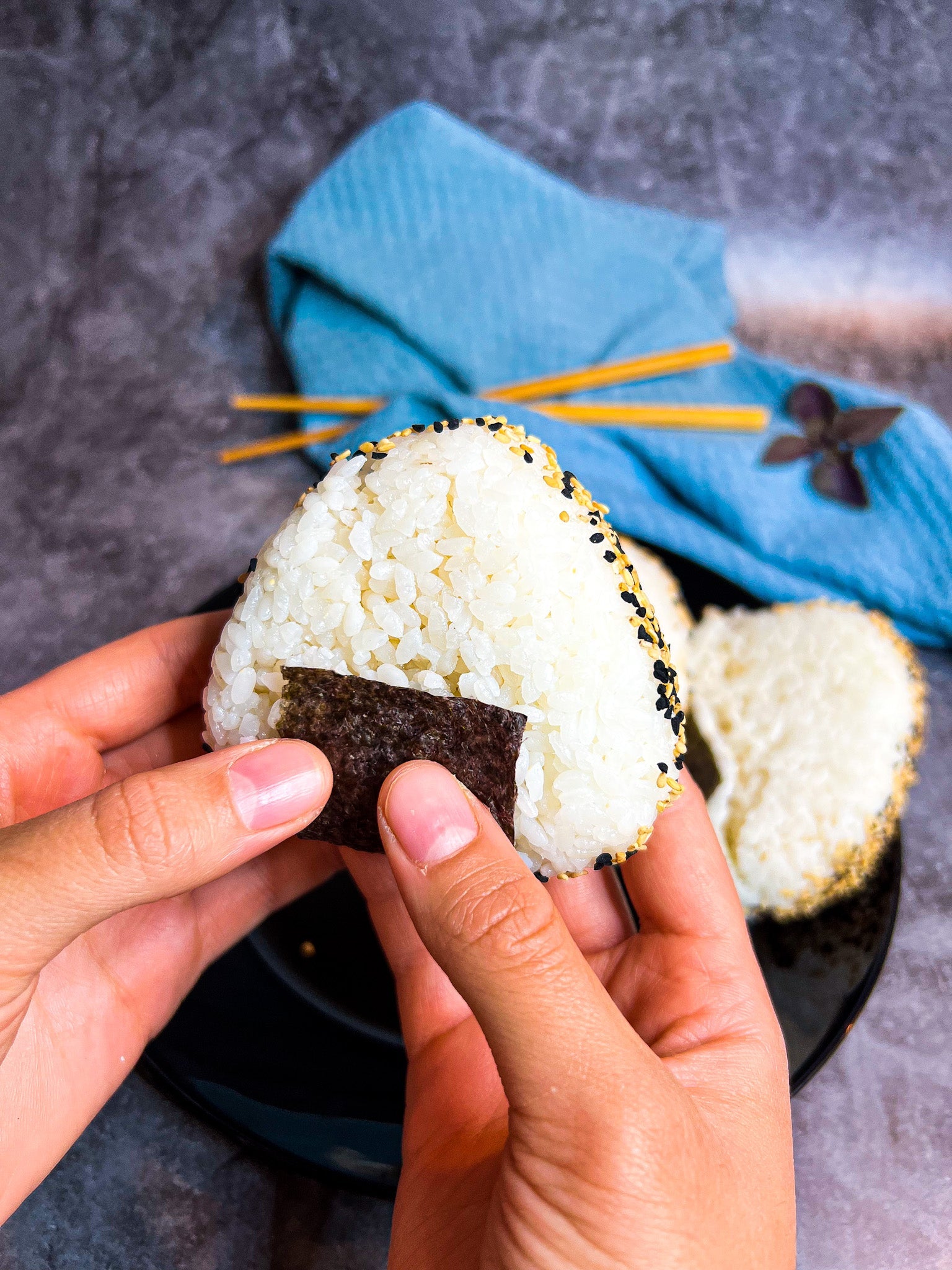 Onigiri-Dreiecke mit Thunfischfüllung, verziert mit Noriblatt und optional in Sesam gewälzt.