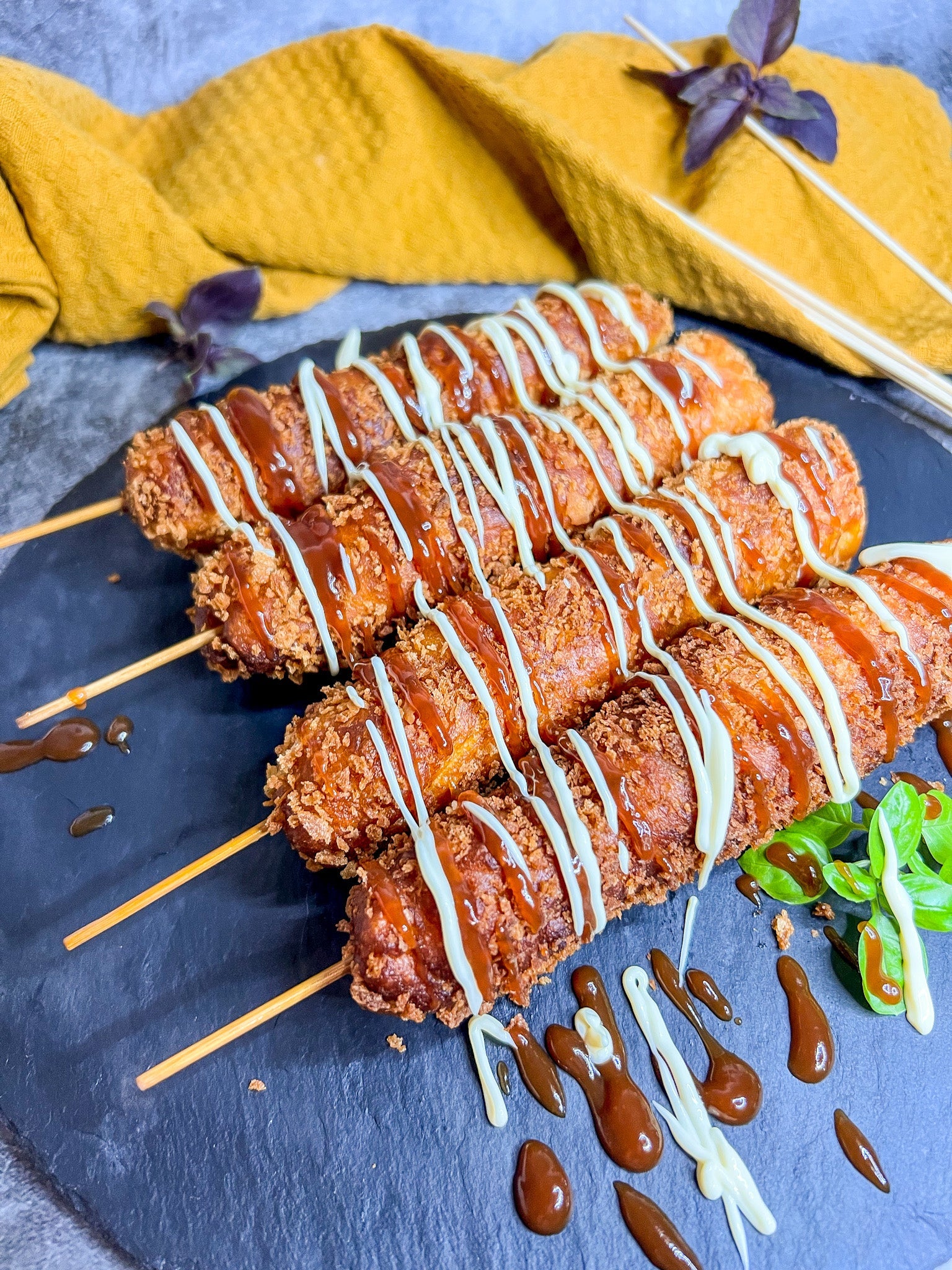 Koreanische Corndogs mit knuspriger Panko-Panade, frittiert und auf einem Holzspieß serviert.