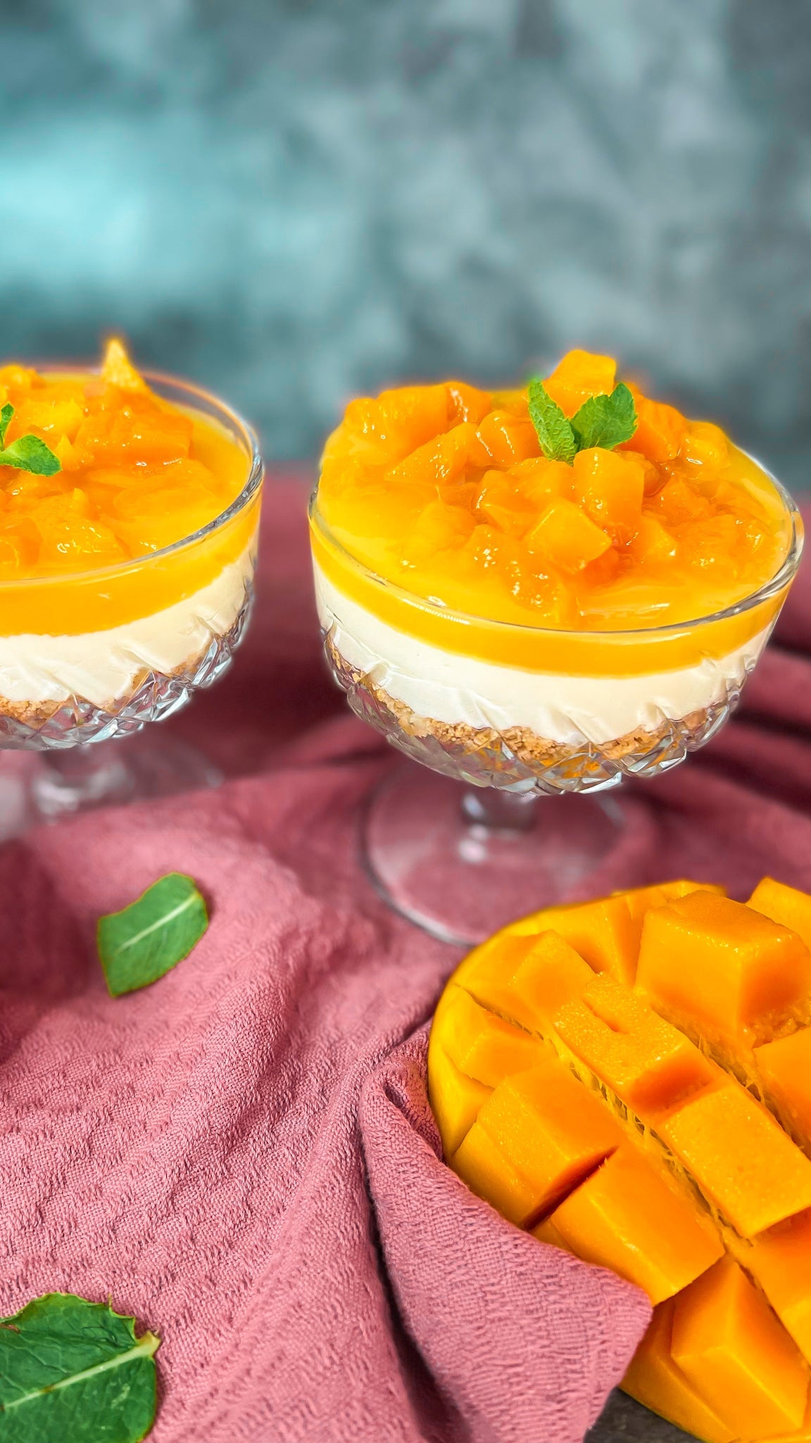 Mango Cheesecake im Glas, dekoriert mit frischen Mangowürfeln und einer leuchtenden Mangoschicht.