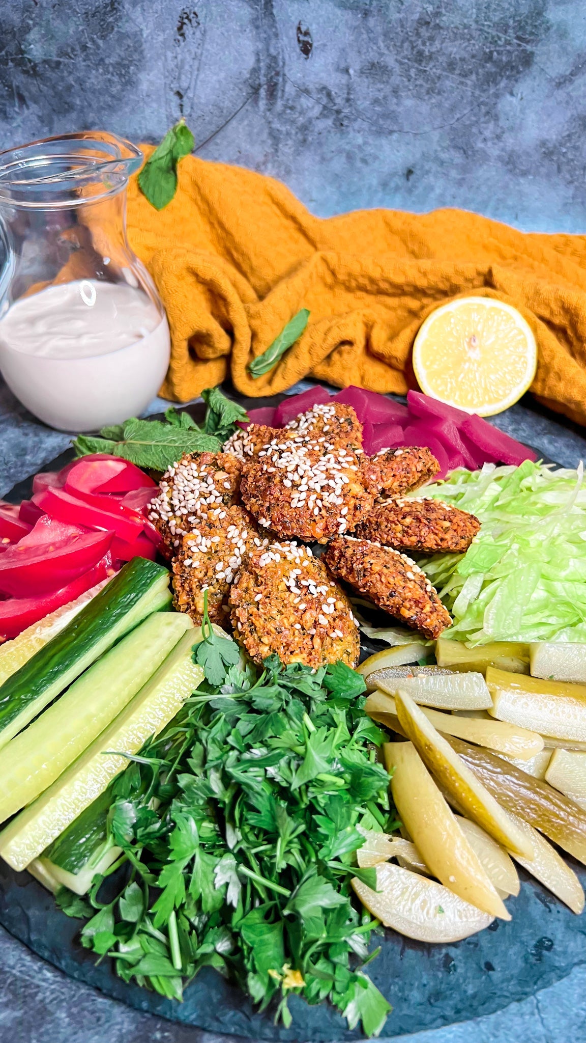 Knusprige Falafelbällchen serviert mit frischem Gemüse, Tahina-Soße und Fladenbrot.