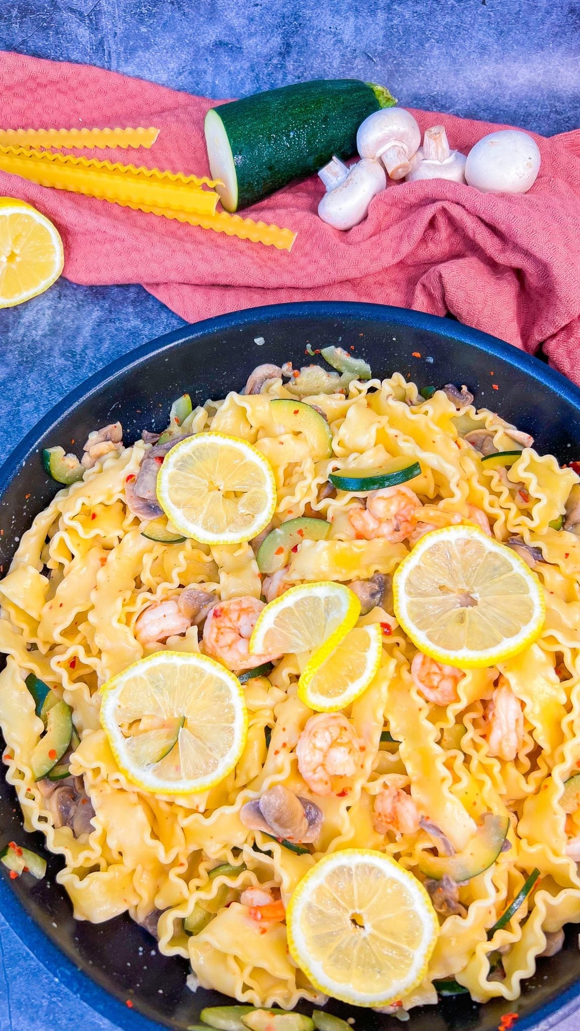 Feurige Garnelen-Zitronen Pasta, serviert mit Zitronenscheiben und Kräutern, auf einem weißen Teller.