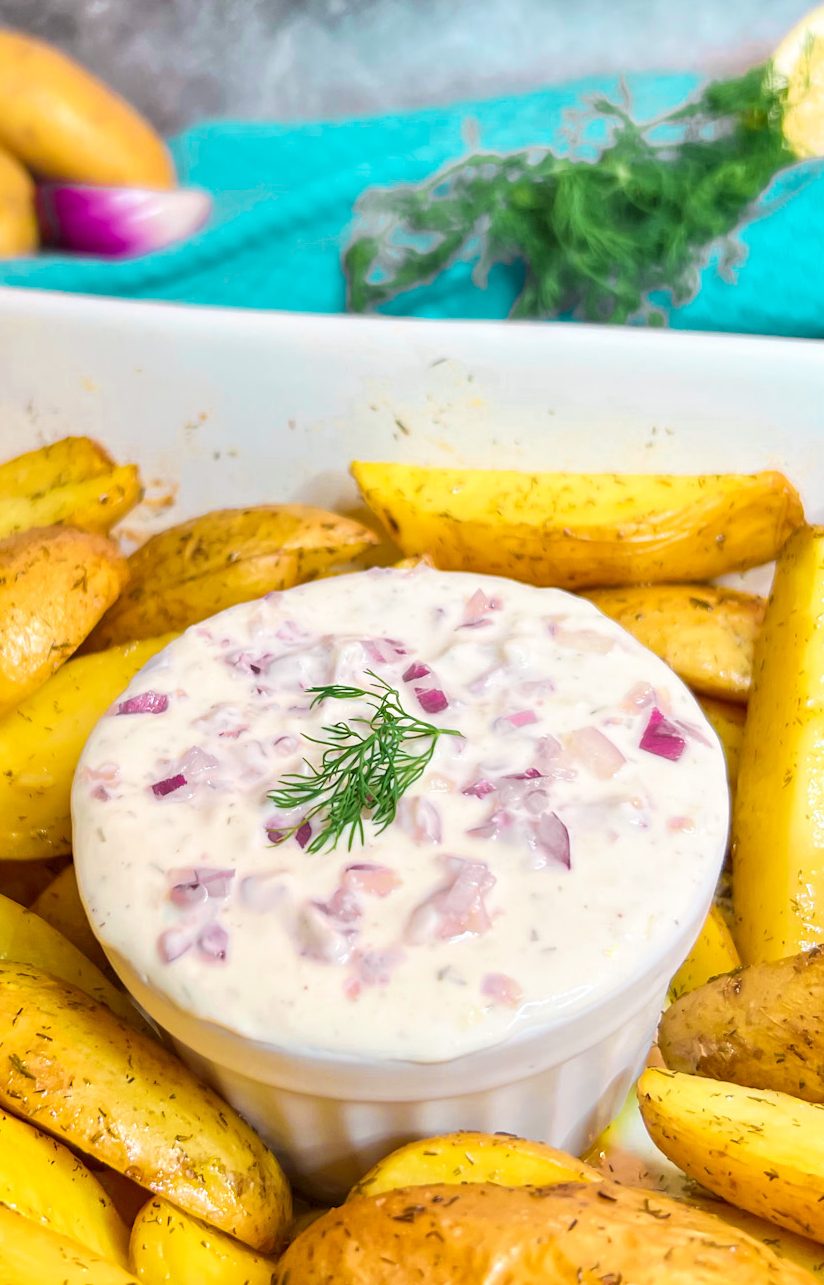 Ein cremiger Sour Cream Dip, garniert mit frischen Kräutern, serviert in einer Schale.