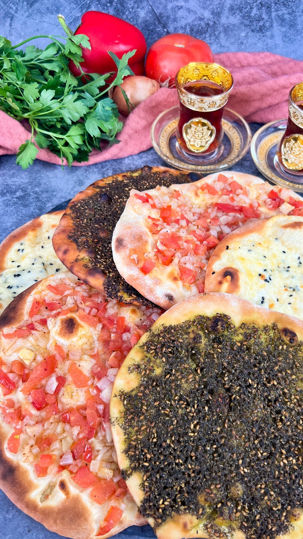 Traditionelle Manakish, belegt mit Zatar, Käse und Tomaten-Zwiebel-Mischung, serviert auf einem Holzbrett.