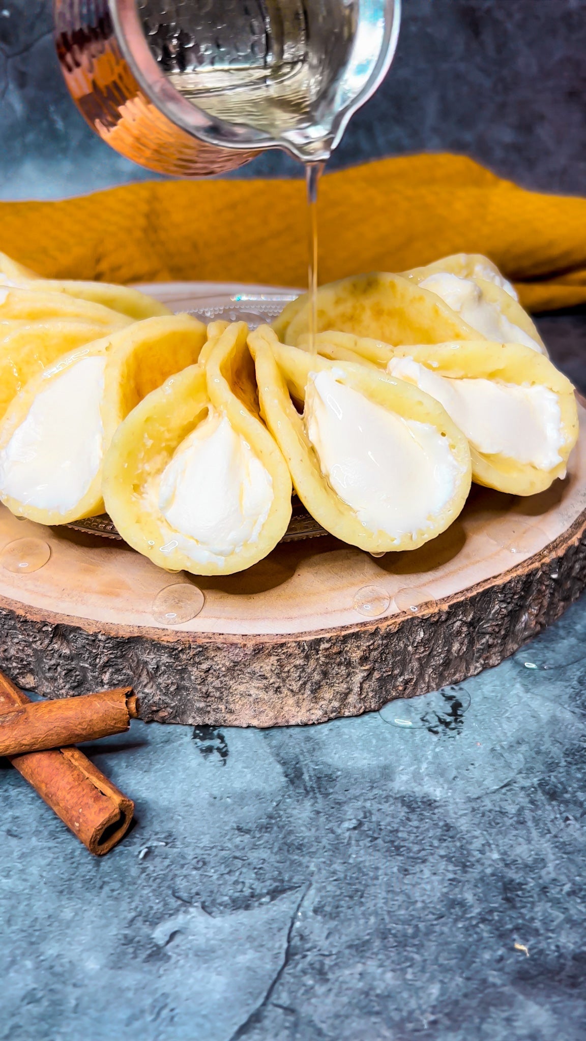 Atayef, gefüllt mit Mascarpone und übergossen mit Zuckersirup, serviert auf einem Teller.