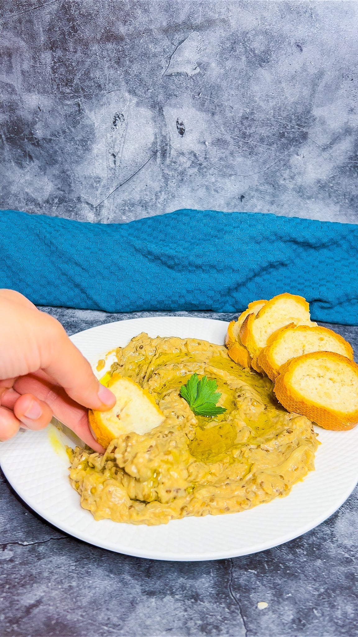 Ein Teller Baba Ghanoush, garniert mit Paprikapulver, Olivenöl und frischen Kräutern, serviert mit Fladenbrot.