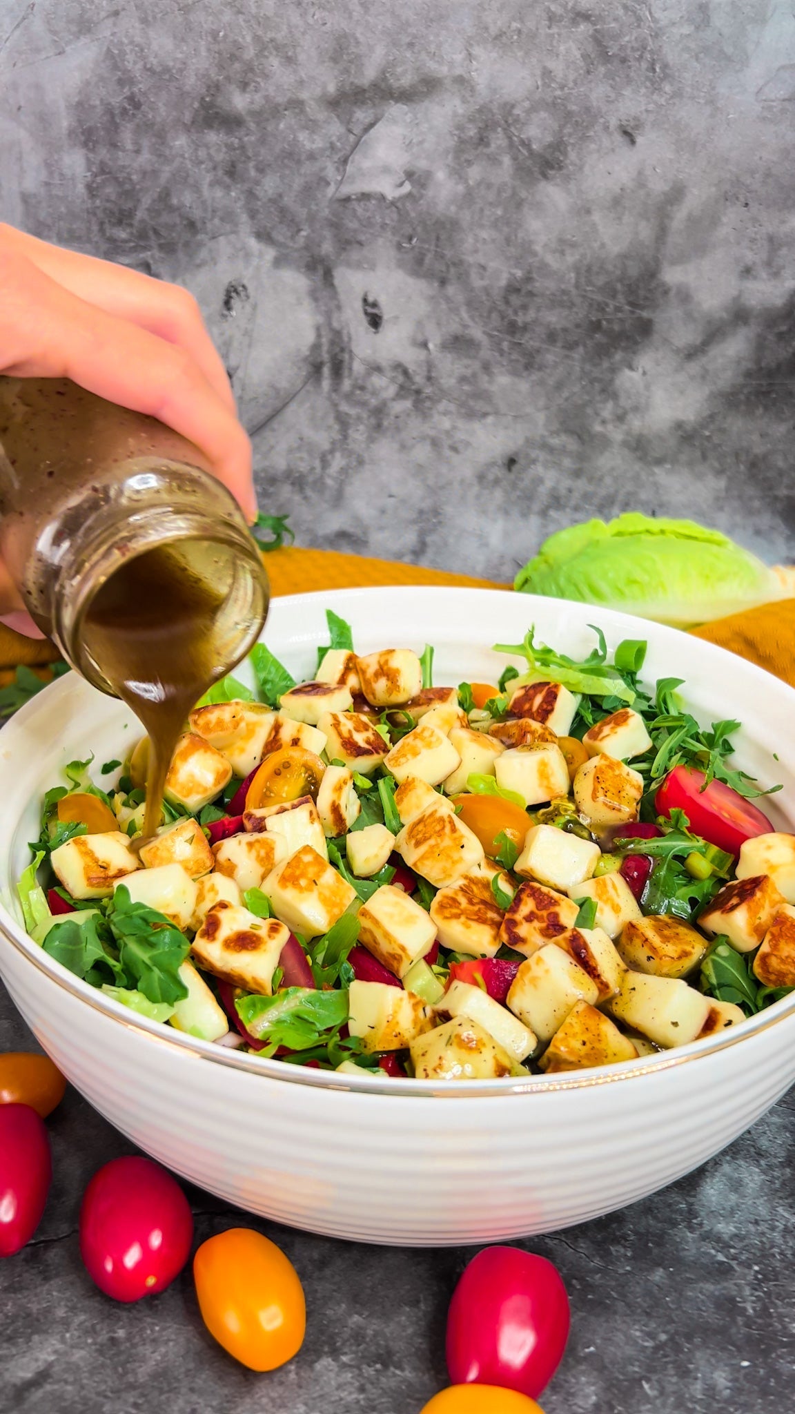 Ein bunter Halloumisalat mit frischen Tomaten, Gurken, Paprika und einem Honig-Zitronen-Dressing, angerichtet in einer Schale.