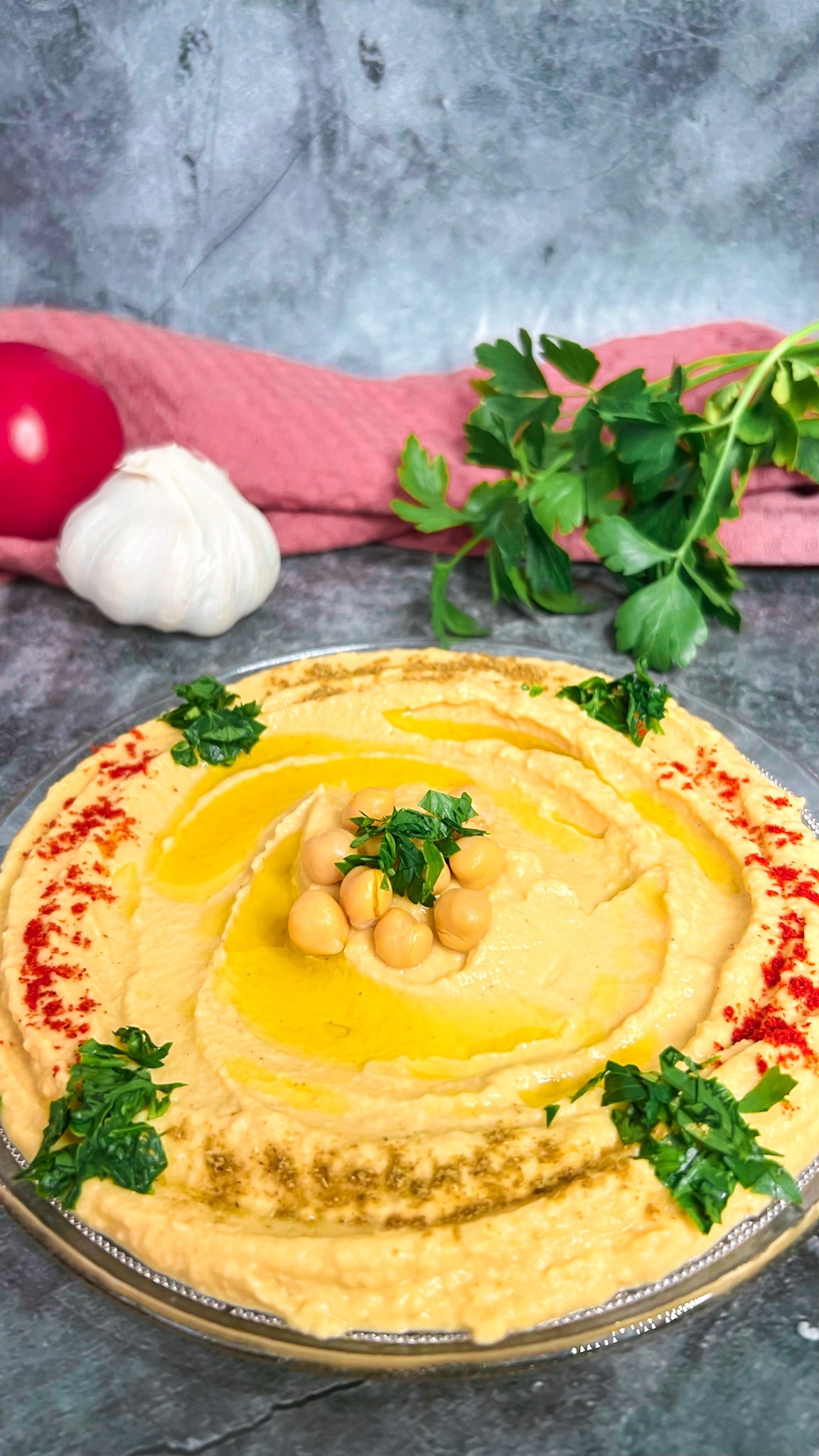 Ein Teller Hummus, garniert mit Olivenöl, Petersilie und Gewürzen, serviert mit Fladenbrot.