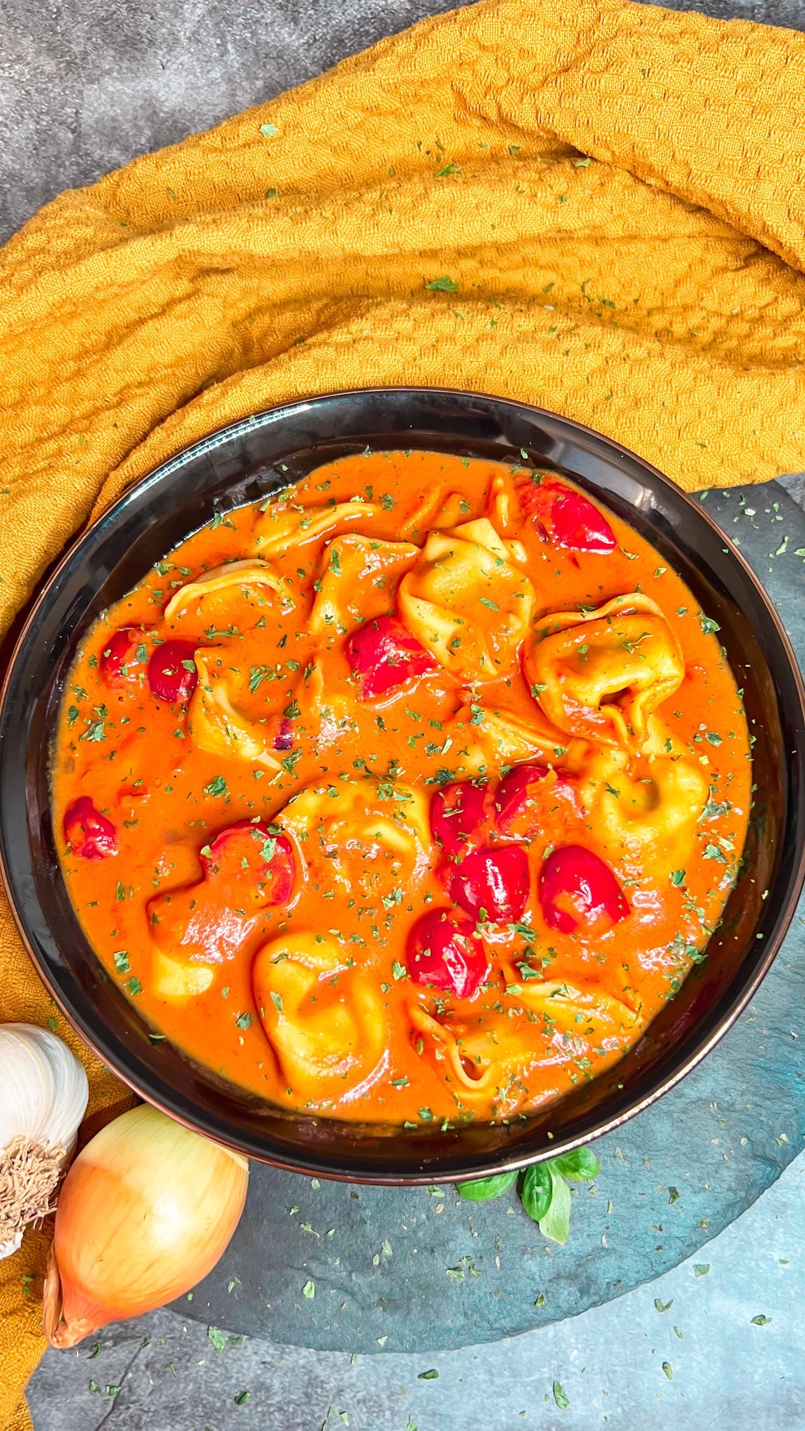 Cremige Tortellinisuppe mit frischen Tomaten und einem Hauch Sahne, serviert in einer Schale.