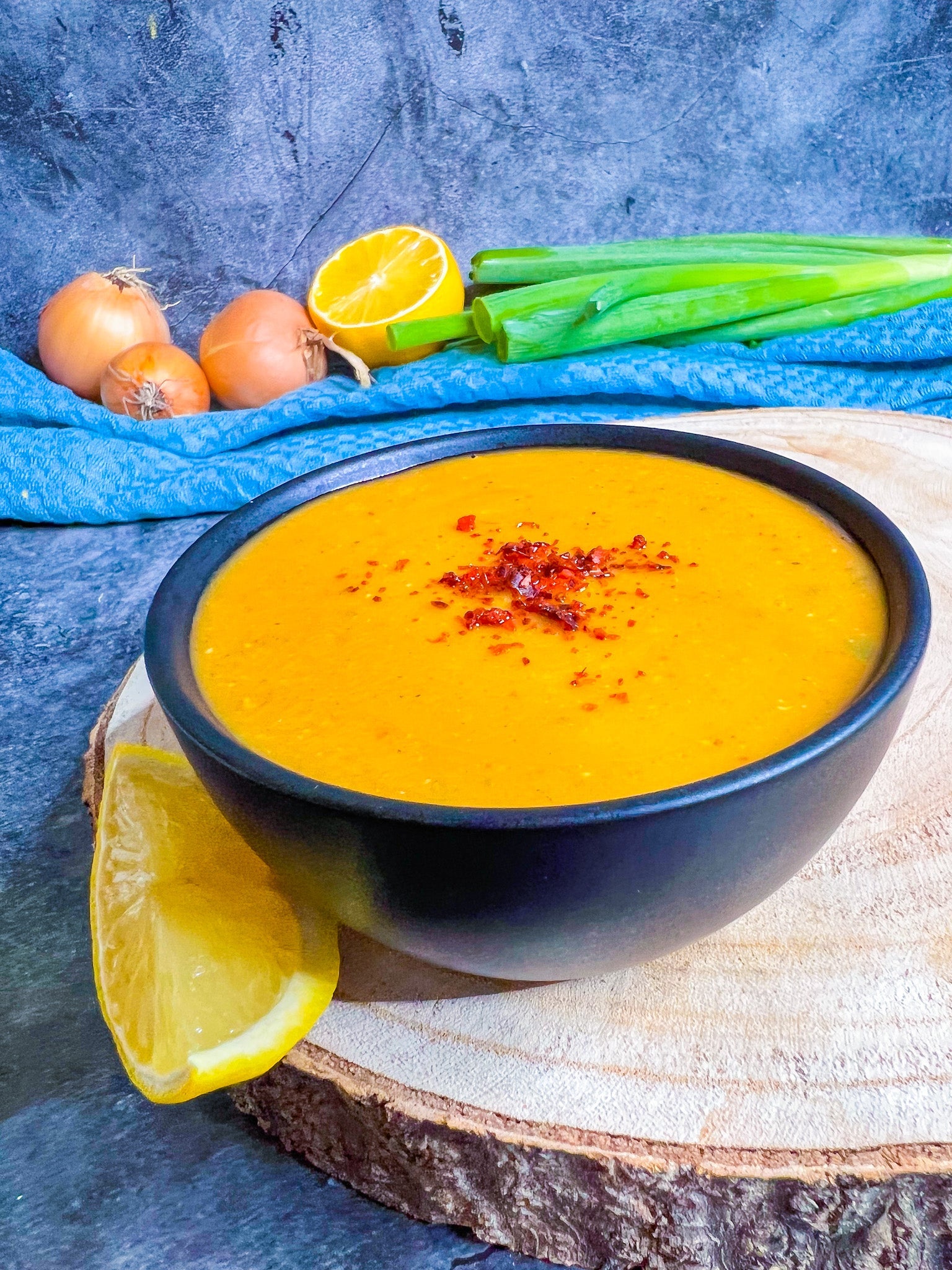 Türkische Linsensuppe mit frischen Zitronenspalten, garniert mit Minze und Paprikaflocken.