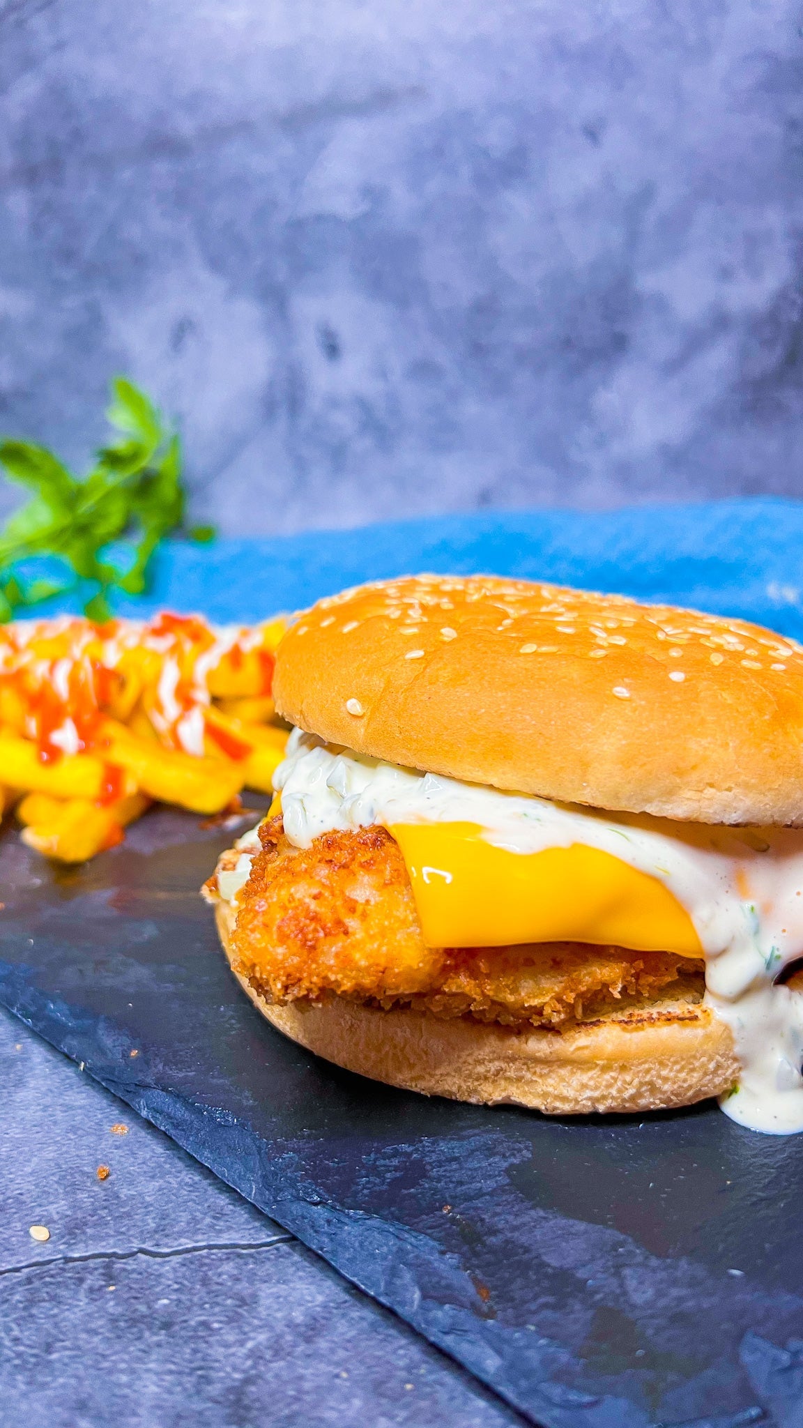 Knuspriger Fish Mac Burger mit Tartarsoße und geschmolzenem Cheddar auf einem goldenen Brötchen.