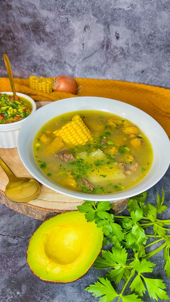 Traditionelle südamerikanische Suppe mit Rindfleisch, Maniok, Kochbananen und Mais, serviert mit frischem Koriander und Avocado.