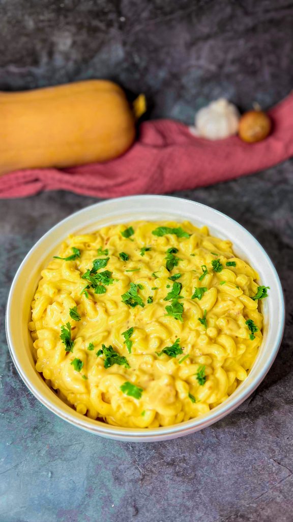 Mac’n’Cheese in einer cremigen Käsesoße, serviert mit goldbraunen Zwiebeln.