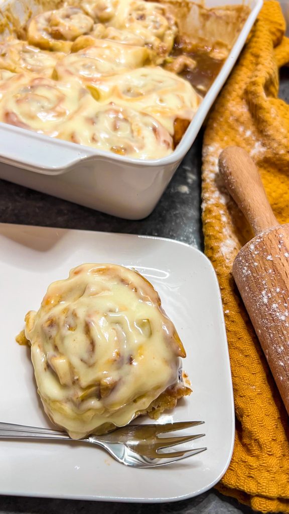 Frisch gebackene, fluffige Zimtschnecken mit Apfelstückchen und Karamellsoße, überzogen mit einem cremigen Frosting.