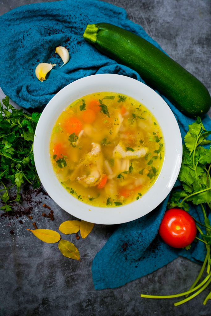 Hausgemachte Hühnersuppe mit frischem Gemüse, Nudeln und aromatischen Gewürzen, serviert in einer rustikalen Schüssel.