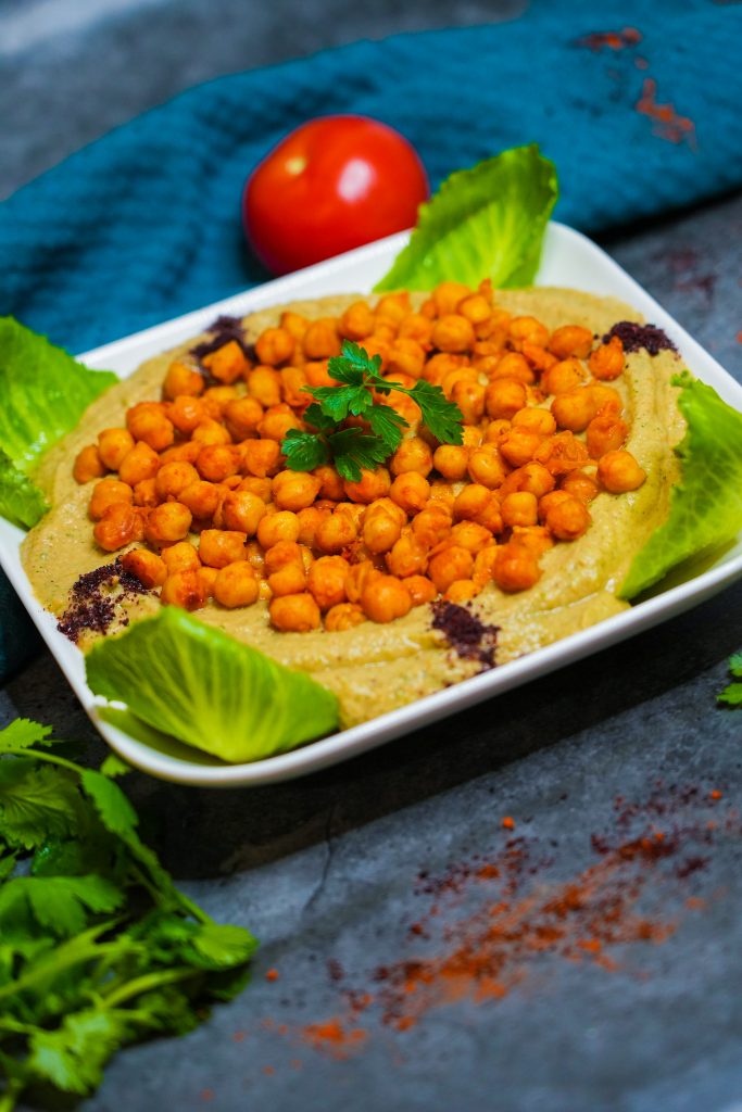 Cremiger Auberginen-Dip mit gerösteten Kichererbsen und frischen Kräutern, serviert auf Romanasalatblättern.