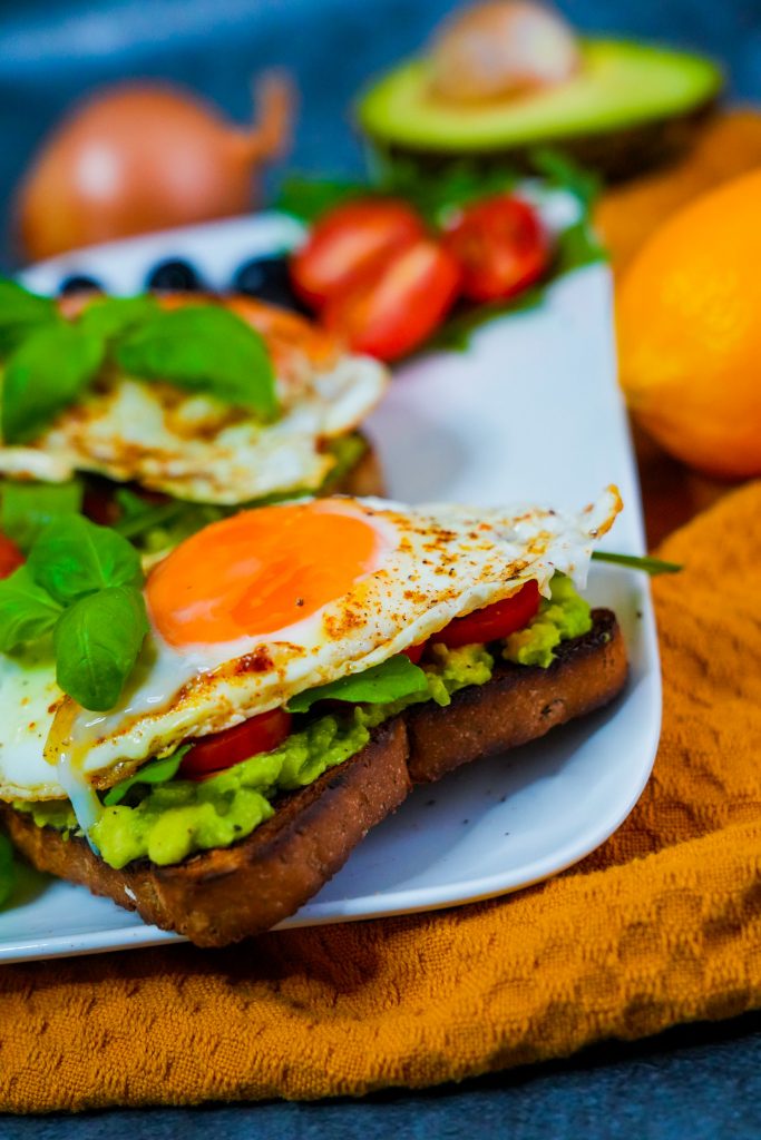 Avocado-Ei Brot mit Rucola und Tomatenscheiben auf knusprigem Toast.