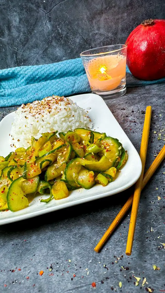 Eine Schale mit würzigem Gurkenkimchi, garniert mit Sesam und Frühlingszwiebeln.