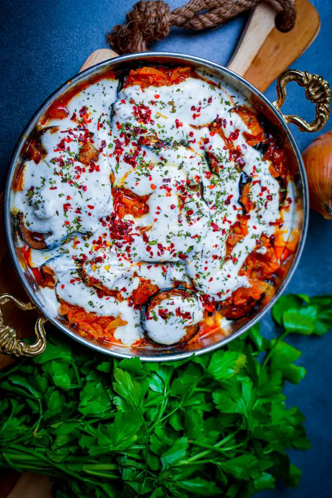 Borani Banjan: Auberginenschichten in würziger Tomatensoße mit cremiger Joghurtsoße.